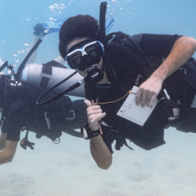 Three Projects Abroad divers swim alongside the camera, taking part in vital marine conservation work in Thailand